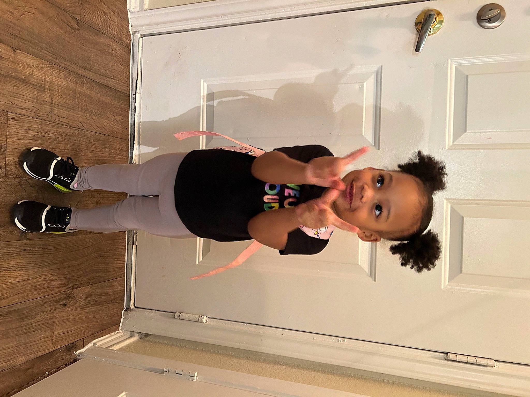 Ariella is registered to the contest to win money with this photo: ceiling, elbow, eyewear, floor, flooring, fun, happy, hardwood, human_leg, joy, knee, person, picture_frame, room, smile, sportswear, t_shirt, thigh, toddler, walking_shoe