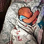 newborn, baby, sleeping, blanket, footprints, pacifier, infant, wrapped, cozy, soft, patterned, lying, peaceful, child, cute, small, indoors, resting, wearing, striped_clothing