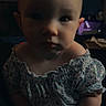 Luna is registered to the contest to win money with this photo: baby, child, infant, face, hands, clothing, floral_pattern, portrait, indoor, shadow, dim_lighting, cute, sitting, young_child, skin, expression, person, small_hands, curious, soft_light