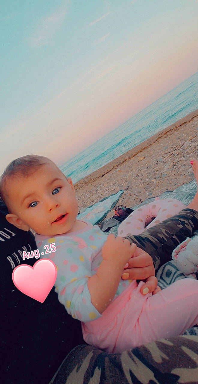 Tess participe au concours pour gagner de l'argent avec cette photo : azure, baby, baby_toddler_clothing, beach, body_of_water, comfort, event, face, fun, happy, horizon, interaction, leisure, morning, people_in_nature, person, sky, sunlight, toddler, travel