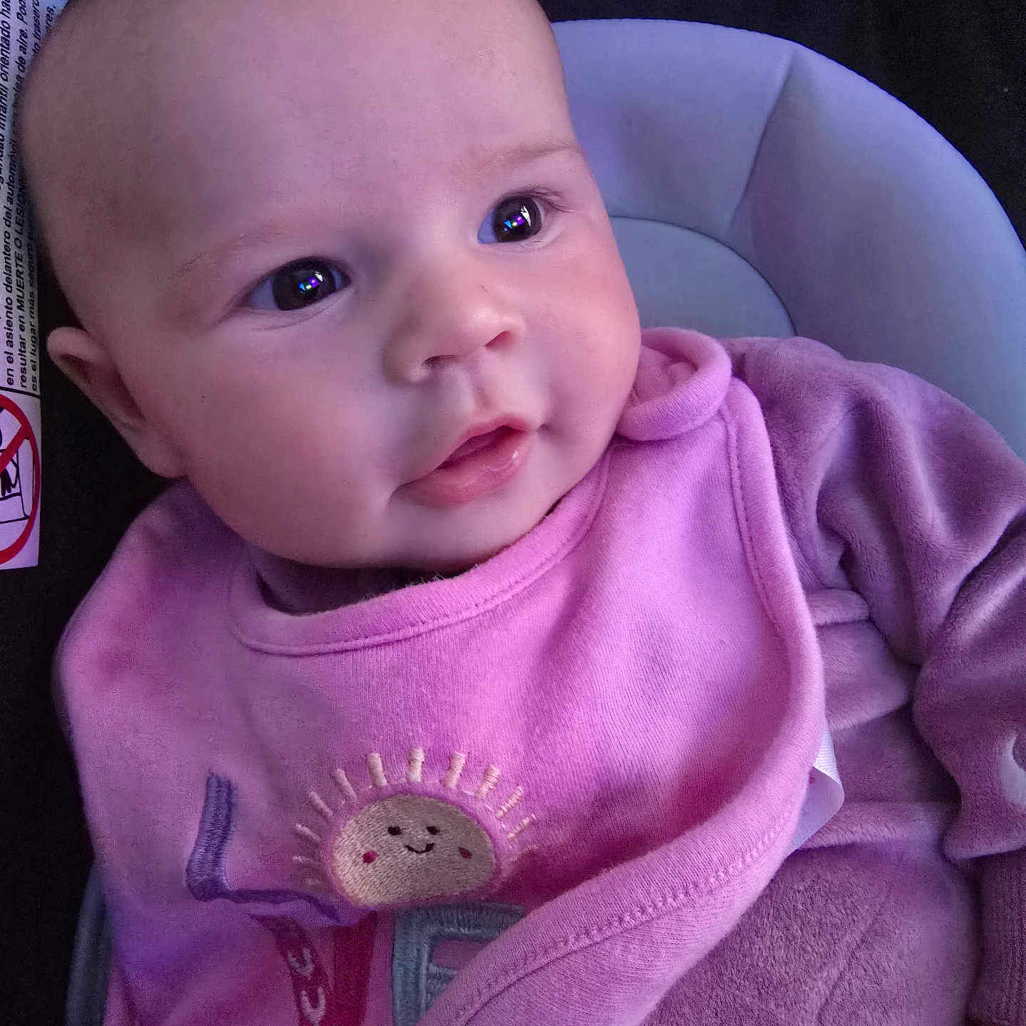 Gianna joined the competition — help win amazing prizes! baby, infant, pink_clothing, bib, smiling_sun, car_seat, face, head, eyes, mouth, cheeks, skin, child, portrait, closeup, young, cute, warm, cozy, indoor