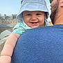 baby, child, smile, hat, bucket_hat, adult, man, beard, glasses, outdoor, sky, buildings, architecture, happy, face, arm, clothing, casual, portrait, daylight