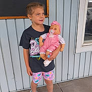 Remi joined the competition — help win amazing prizes! casual_clothing, child, concrete, daylight, doll, girl, hair_braids, headband, holding, light_blue, outdoor, pacifier, playful_expression, shorts, side_gaze, sneakers, standing, toy, wall, window