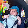 baby, child, car_seat, blue_hat, safety_straps, toy, colorful, infant, outdoor, sun_hat, cute, face, seat, clothing, hands, legs, comfort, protection, expression, parenting