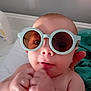 baby, sunglasses, face, hand, skin, infant, portrait, cute, expression, indoor, person, newborn, glasses, closeup, child, young, small, fist, soft_light, bed