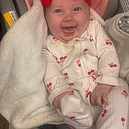 Andi is registered to the contest to win money with this photo: baby, child, infant, smiling, happy, portrait, car_seat, red_bow, headband, blanket, onesie, patterned_clothing, cozy, seated, indoors, vehicle, face, eyes, open_mouth, photography