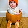 baby, child, pumpkin, orange_hat, striped_leggings, smiling, happy, indoor, floor, wooden_floor, cute, portrait, hat, sitting, seasonal, fall, autumn, cozy, playful, infant