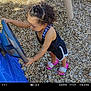 toddler, child, curly_hair, playground, steering_wheel, wood_chips, pink_sandals, black_outfit, outdoor, summer, play, person, young_child, fun, daylight, toy, footwear, casual_clothing, activity, recreation
