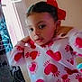 Ashanti joined the competition — help win amazing prizes! child, heart_pattern, hoodie, red_bow, indoor, window, blanket, pajamas, face, person, cute, cozy, natural_light, bedroom, smiling, young_child, colorful, soft_light, casual_clothing, portrait