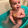 baby, bathtub, water, toy, child, sitting, bath, happy, skin, face, expression, indoor, curly_hair, naked, toddler, blue, yellow, play, cute, infant
