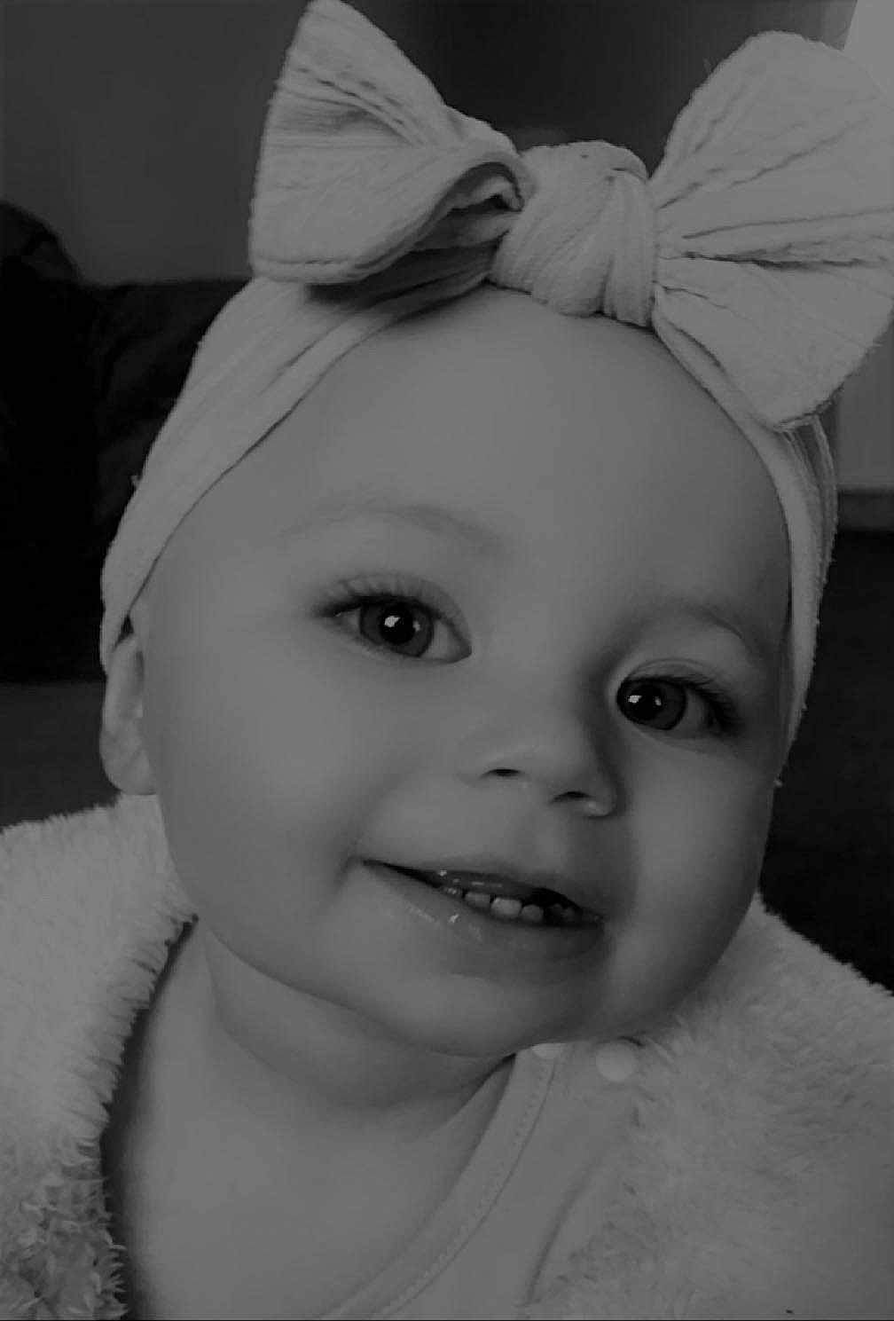 Esme is registered to the contest to win money with this photo: baby, child, smiling, headband, bow, close_up, face, eyes, teeth, infant, portrait, cute, adorable, black_and_white, clothing, soft_texture, young, happy, indoors, person