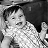 Sacha a rejoint le concours — aidez-le/la à gagner de superbes lots ! baby, bib, black_and_white, checkered_pattern, child, clothing, cute, expression, face, hand, happy, high_chair, indoor, infant, person, portrait, seat, smiling, table, young