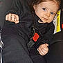 toddler, child, car_seat, black_clothing, hair_tie, seatbelt, warning_label, blue_eyes, indoor, portrait, baby, straps, safety, young_child, cute, person, seat, car, casual, relaxed