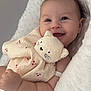 baby, smiling, plush_toy, blanket, cute, child, soft_texture, happy, face, infant, closeup, cozy, comfort, lying_down, skin, expression, adorable, peaceful, indoor, young_child