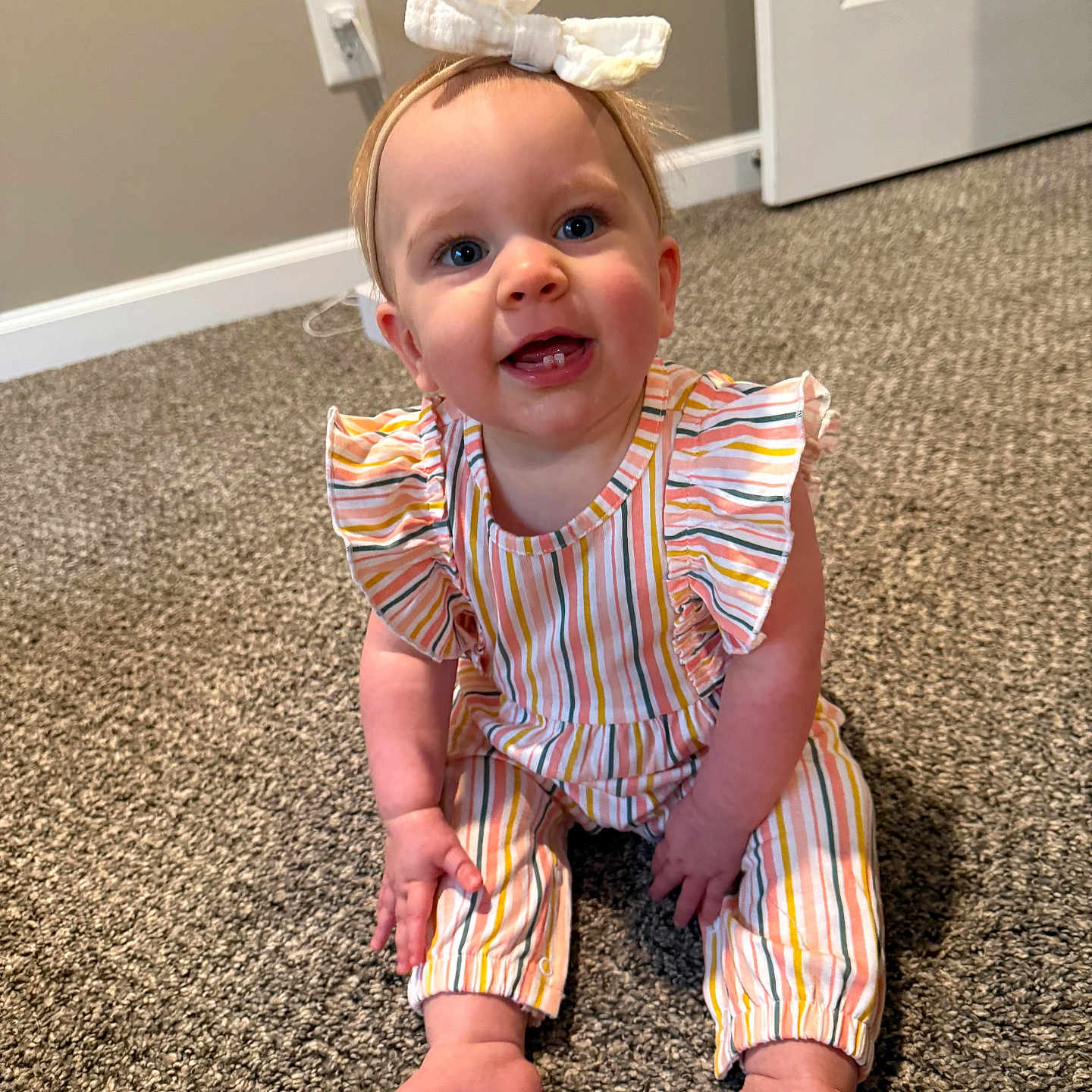 Morgan is registered to the contest to win money with this photo: baby, bow, carpet, child, cute, door, face, floor, hand, happy, headband, indoor, infant, person, room, sitting, smiling, striped_clothing, toes, young_child