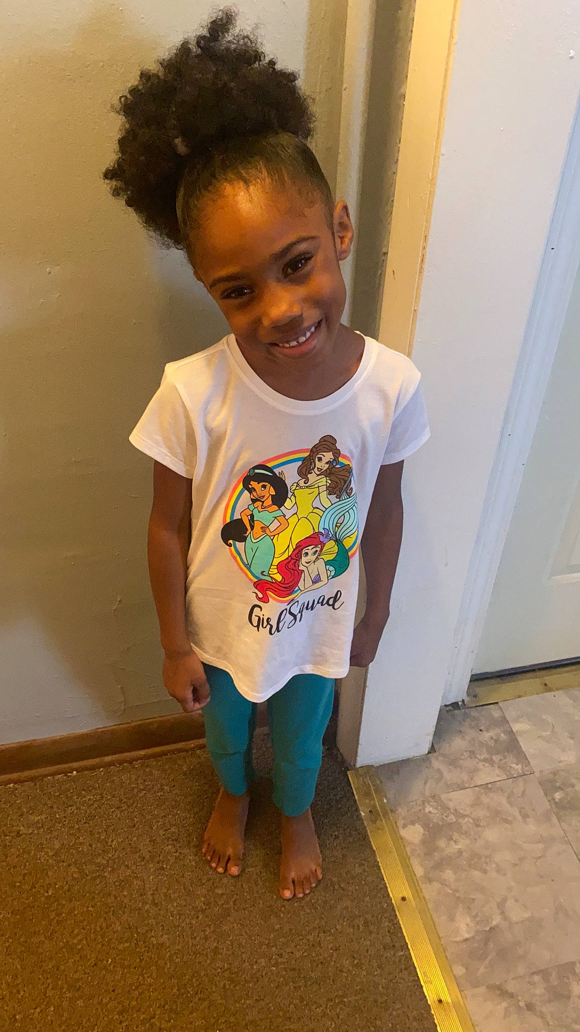 Cassidy is registered to the contest to win money with this photo: arm, baby_toddler_clothing, door, face, floor, flooring, hair, hairstyle, happy, head, joint, joy, neck, nose, person, shoulder, skin, sleeve, smile, standing