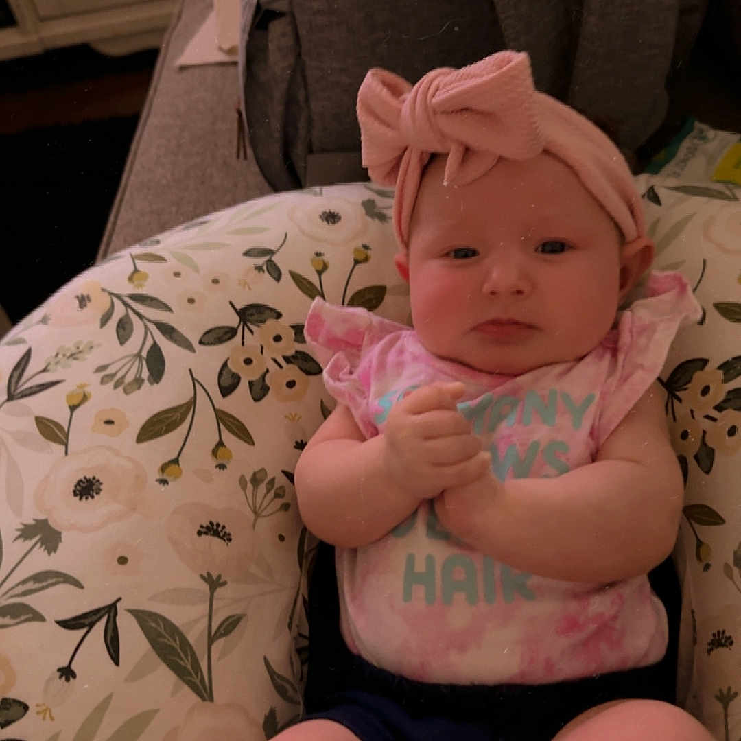 Harlow is registered to the contest to win money with this photo: baby, bodypart, bonnet, cap, car, car_interior, carseat, clothing, couch, cushion, face, finger, furniture, hand, hat, head, homedecor, newborn, person, transportation