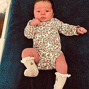 Arya participe au concours pour gagner de l'argent avec cette photo : baby, infant, child, onesie, floral_pattern, white_socks, blanket, blue_blanket, lying_down, indoor, person, cute, newborn, portrait, clothing, skin, head, face, expression, hand