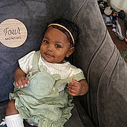 Freya Handy is registered to the contest to win money with this photo: baby, infant, child, smiling, headband, green_dress, socks, chair, plush, milestone, wooden_plaque, indoor, cute, portrait, person, happy, sitting, young_child, comfortable, home