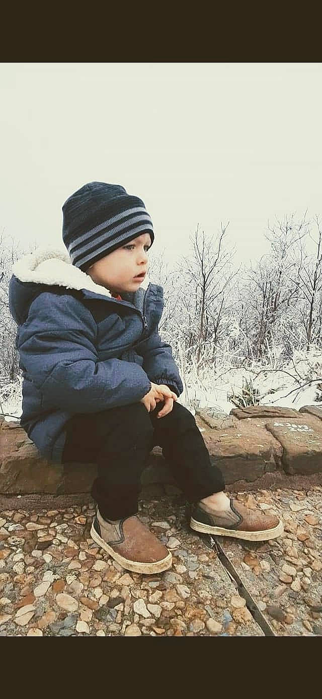 Clay is registered to the contest to win money with this photo: baby, baby_toddler_clothing, beanie, bonnet, child_model, footwear, freezing, headwear, hood, jacket, leg, outdoor_shoe, person, photo_shoot, portrait_photography, shoe, sitting, trousers, walking_shoe, winter