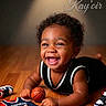 Kayoir joined the competition — help win amazing prizes! baby, child, smiling, laughing, portrait, basketball, sports, jersey, rookie, sneakers, indoor, wood_floor, curly_hair, happy, sitting, crawling, infant, black_clothing, basketball_theme, text_overlay