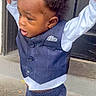 Kayoir is registered to the contest to win money with this photo: child, toddler, boy, portrait, standing, outdoor, suit, vest, bow_tie, formalwear, navy_blue, curly_hair, smiling, tongue_out, earring, fashion, doorway, concrete, adult_hand, tiktok_watermark