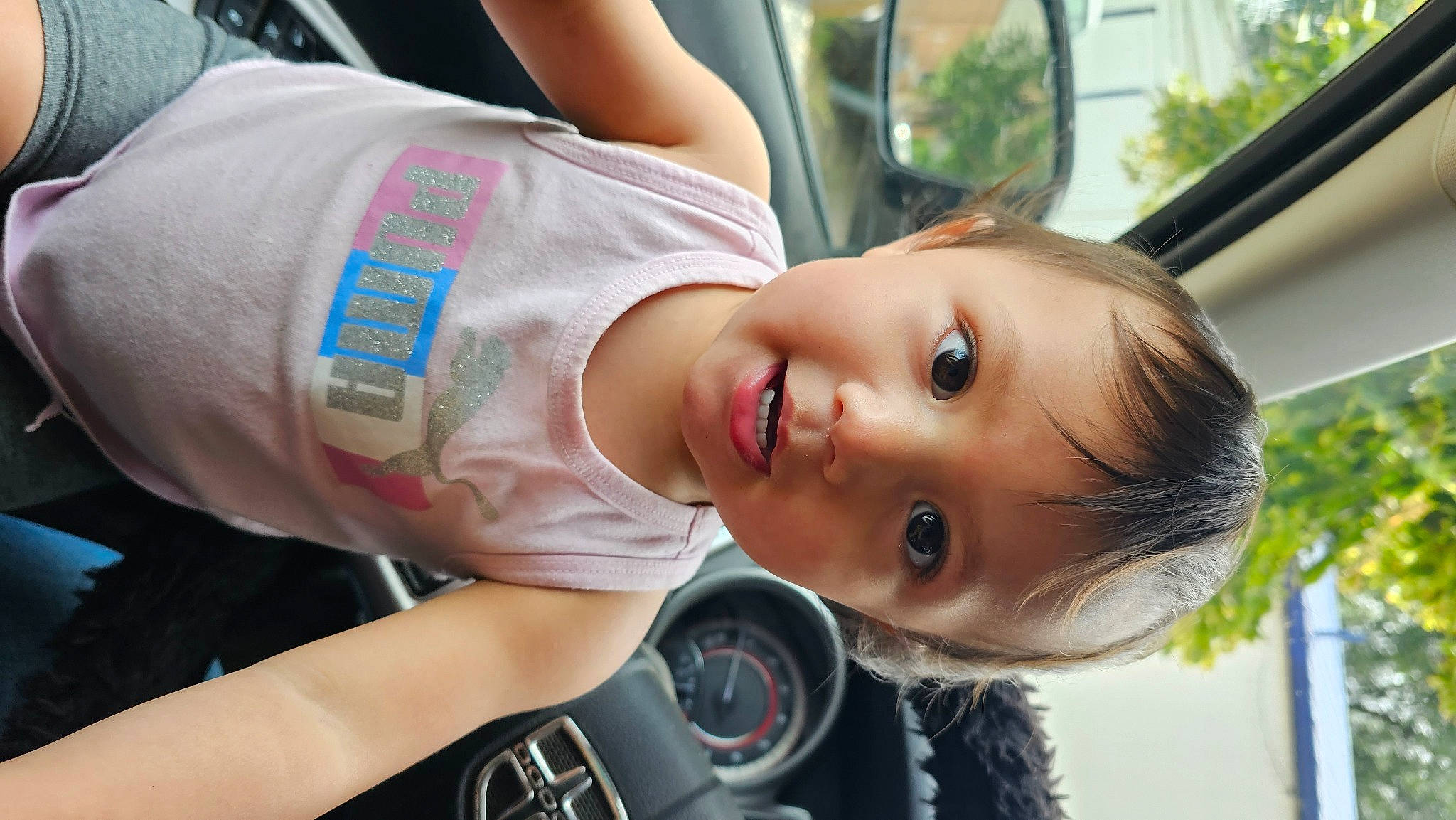 Skylar is registered to the contest to win money with this photo: automotive_lighting, automotive_tire, child, dress, elbow, eye, fun, gesture, happy, head, motor_vehicle, person, plant, rim, skin, smile, tire, toddler, tree, wheel