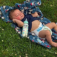 Promise is registered to the contest to win money with this photo: baby, blanket, bottle, child, clothing, comfort, cute, diaper, grass, greenery, infant, lying_down, milk, nature, outdoor, peaceful, relaxing, resting, sleeping, soft