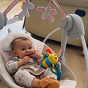 Aïla participe au concours pour gagner de l'argent avec cette photo : baby, infant, baby_seat, toy, plush_toy, smiling, indoors, flooring, sofa, child, cute, comfort, home, wood_floor, clothing, socks, playful, relaxed, furniture, person