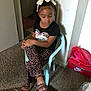 Zaniyah joined the competition — help win amazing prizes! child, girl, indoor, sitting, chair, curly_hair, bow, leopard_print, pants, black_shirt, cat_design, footwear, sandals, carpet, nike_box, shoes, wall, room, thoughtful, crossed_legs