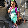 Zaniyah joined the competition — help win amazing prizes! child, girl, outdoor, sunlight, fence, chain_link, backpack, phone, green_bow, shorts, sandals, concrete, shelf, shadow, curly_hair, casual_clothing, playful, standing, person, daytime
