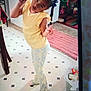 Zaniyah is registered to the contest to win money with this photo: child, girl, yellow_top, patterned_pants, peace_sign, posing, indoor, tiled_floor, pink_rug, toys, braided_hair, home, trash_can, playful, smiling, person, young, cute, floor, furniture