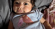 Areli joined the competition — help win amazing prizes! baby, infant, child, onesie, striped_clothing, owl_print, bed, pillow, blanket, indoor, person, portrait, cute, smile, lying_down, young_child, skin, face, hand, casual