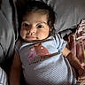 baby, infant, child, onesie, striped_clothing, owl_print, bed, pillow, blanket, indoor, person, portrait, cute, smile, lying_down, young_child, skin, face, hand, casual