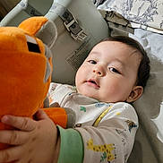 Emilio joined the competition — help win amazing prizes! baby, bed, bedding, booster_seat, child, comfort, cozy, cute, face, hand, indoor, infant, orange, pajamas, person, plush_toy, resting, sleepwear, soft_toy, young_child