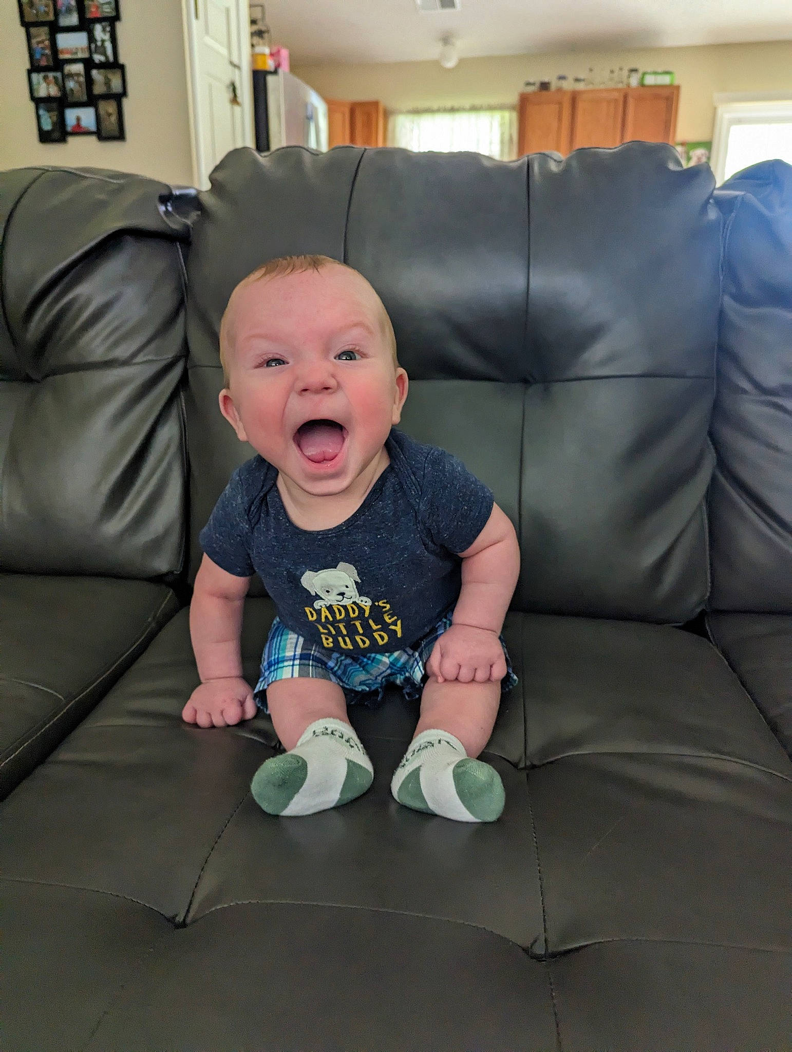 Killian is registered to the contest to win money with this photo: baby, baby_toddler_clothing, chair, child, comfort, couch, flooring, fun, grass, happy, living_room, person, picture_frame, room, sitting, sleeve, smile, sock, t_shirt, toddler