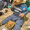 child, toddler, birthday, boy, cake, frosting, eating, smiling, sitting, party, blue_outfit, ribbon, indoors, carpet, dessert, food, finger_food, messy, playpen, celebration