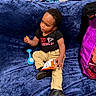 Veyquan joined the competition — help win amazing prizes! child, toddler, baby, sitting, portrait, face, smiling, snack, chips, food, snack_bag, toy, blue_toy, blanket, couch, indoor, black_shirt, khaki_pants, black_shoes, colorful_background