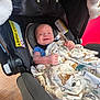 baby, infant, car_seat, blanket, smile, happy, child, indoor, clothing, fabric, seat, safety, cute, person, head, comfort, pattern, animal_print, pacifier, wood_floor