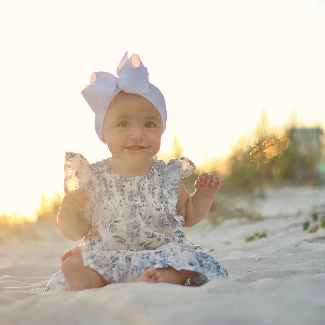 Gradie is registered to the contest to win money with this photo: baby, beach, bow, candid, child, cute, dress, grass, happy, headband, infant, nature, outdoor, portrait, sand, sitting, smile, summer, sunlight, sunset