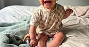 Gradie is registered to the contest to win money with this photo: baby, bed, blanket, child, clothing, cozy, cute, feet, hand, happy, head, indoors, infant, person, portrait, room, sitting, skin, smiling, toy