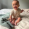baby, bed, blanket, child, clothing, cozy, cute, feet, hand, happy, head, indoors, infant, person, portrait, room, sitting, skin, smiling, toy