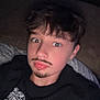 child, boy, selfie, indoors, couch, black_sweatshirt, text_on_clothing, facial_hair_drawn, mustache, goatee, casual, young, portrait, face, hair, relaxed, seated, funny, expression, home