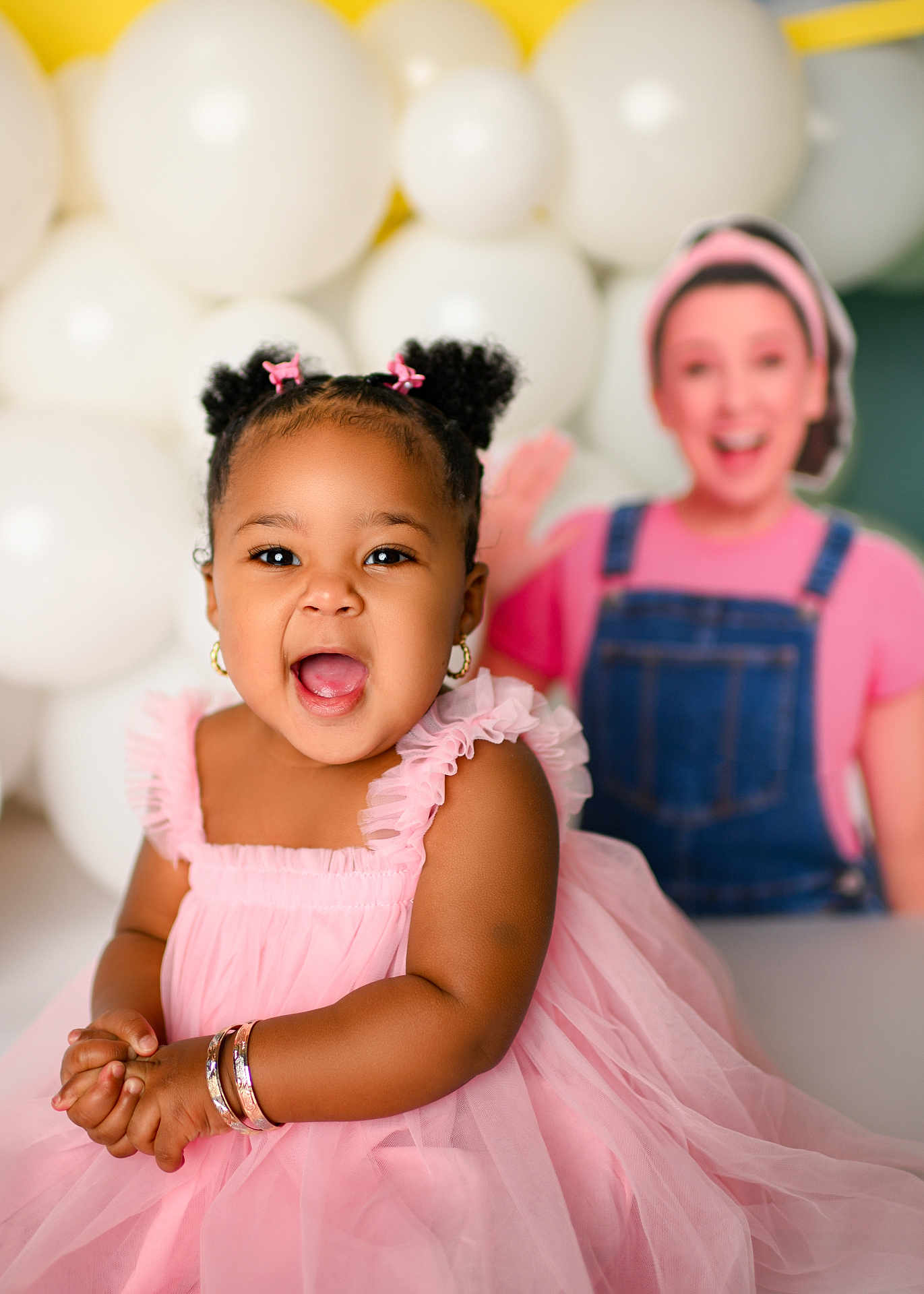 Lannie joined the competition — help win amazing prizes! toddler, child, pink_dress, smiling, happy, bracelets, hair_buns, earrings, balloons, yellow_background, person, portrait, indoor, cute, celebration, clothing, accessories, baby, joy, fun