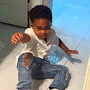 Jace is registered to the contest to win money with this photo: child, boy, indoor, floor, tile_floor, white_sweater, ripped_jeans, sneakers, nike, green, white, smiling, reaching, playing, casual_clothing, young_child, curly_hair, door, reflection, pose