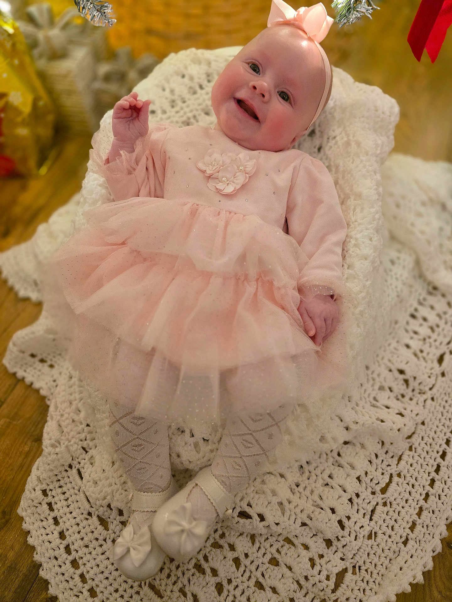 Rosie joined the competition — help win amazing prizes! baby, infant, pink_dress, headband, smiling, crocheted_blanket, white_shoes, tights, indoor, floor, wooden_floor, portrait, cute, happy, child, person, soft_lighting, cozy, celebration, holiday_decor