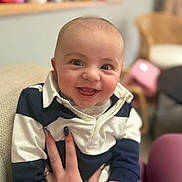Eden participe au concours pour gagner de l'argent avec cette photo : baby, infant, smiling, face, eyes, portrait, hand, nail_polish, striped_shirt, collar, couch, indoor, bokeh, blurred_background, happy, cheek, sitting, person, chair, soft_lighting