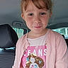 child, girl, car_interior, pink_cardigan, sequin_tshirt, mermaid_design, smile, face, hair, window, seat, clothing, young, casual_wear, portrait, happy, indoors, person, cute, fashion