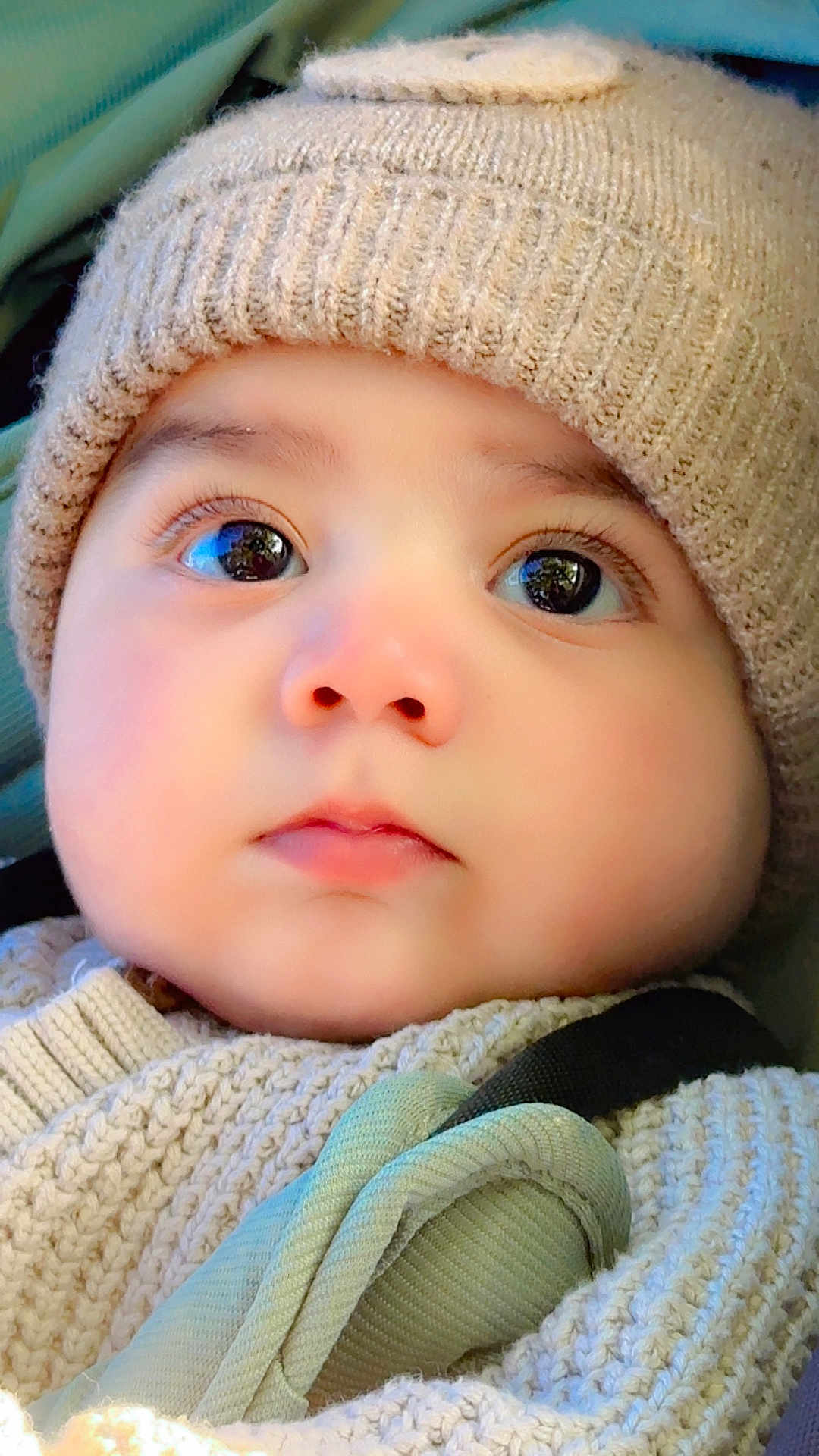 Yahya is registered to the contest to win money with this photo: baby, closeup, face, hat, knitted, sweater, child, infant, cute, cozy, warm, portrait, young, gaze, eyes, soft_lighting, expression, skin, headwear, bundle