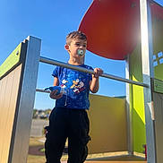 Rehan participe au concours pour gagner de l'argent avec cette photo : child, boy, playground, outdoor, toy, pacifier, blue_sky, tshirt, sonic_the_hedgehog, black_pants, sneakers, metal_rail, shade, sunlight, daytime, play_equipment, casual_clothing, young, standing, holding